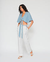 Full-length view of Carolina blue gingham tie front crop top styled with white linen wide-leg pants and minimalist sandals.