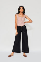 Full-length studio portrait of a woman modeling the red and white striped Ines bustier top paired with high-waisted wide-leg black trousers.