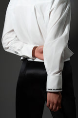 Rear view of a woman with her hand behind her back, showcasing the box pleat on the back yoke and embroidered detailing on the sleeve cuff.