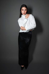 Image of a model posing in a white cropped button-down shirt with black embroidered cuffs and high-rise black pants by Cindy Castro New York.