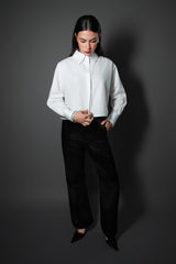 Full length photo of a woman wearing the Cindy Castro New York white cropped shirt with signature embroidery, black tailored trousers, and black pointed heels.