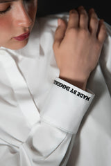 Close up image of the embroidered text on the sleeve of the made by immigrants button down shirt by Cindy Castro New York
