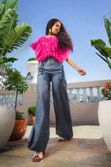 Andrea high waisted wide leg denim pants paired with vibrant pink ruffle blouse creating a bold contemporary statement look outdoors.