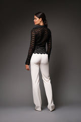 Rear studio perspective of a model showcasing the scalloped eyelash lace hemline, pointed collar, and fitted silhouette of the black Joan sheer top.
