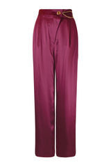 Woman wearing high-waisted, wide-leg silk purple trousers with a sleek, flowy silhouette, featuring gold accents and front pleats for a polished, comfortable look.