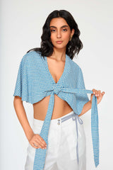 Model wearing Carolina blue gingham tie front crop top with white linen pants featuring wide sleeves and relaxed silhouette.
