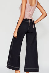 Rear close-up studio shot showcasing the back clean design of the black Erika wide-leg pants, featuring prominent white contrast topstitching.