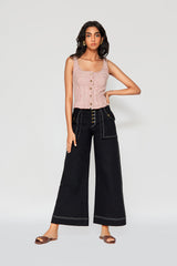 Full-length studio portrait of a model against a white backdrop, showcasing the front button fly closure, oversized utility pockets, and relaxed silhouette of the black Erika denim pants.