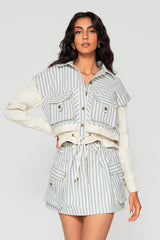 Three-quarter studio portrait of a woman wearing the Cindy Castro Giani Denim Jacket in blue and white vertical stripes with matching Mati denim mini skirt.