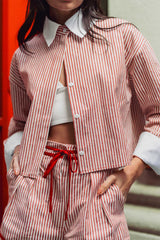 Close up of Cindy Castro New York red striped high waisted shorts highlighting pleats, contrast piping, side pockets, and ribbon waist tie.
