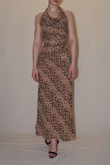 Full-length linesheet studio shot of a model presenting the front view of the leopard print Jolene dress, showcasing its draped cowl neckline and fluid ankle-length maxi silhouette.