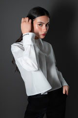 Side profile image of a model showcasing the loose, tailored sleeves and custom embroidered cuffs of a premium white poplin button down shirt by Cindy Castro New York.