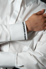 Close up image with the different angle of the embroidered text on the sleeve of the made by immigrants button down shirt by Cindy Castro New York