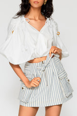 Mati Denim Skirt in blue stripe paired with white blouse featuring cargo pockets, front zipper, and adjustable waist tie.