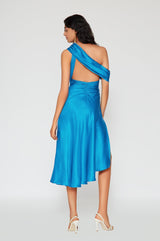 Back view of the Rebecca blue one shoulder satin midi dress featuring open back, ruched waist, asymmetrical design, and flowing hemline.