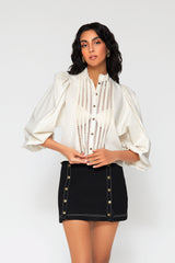 Three-quarter studio portrait of a woman modeling the black Sofia denim skirt styled elegantly with an ivory open-work cotton lace blouse.