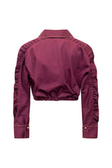 Clean studio product view showcasing the back profile of the plum violet cropped jacket shirt, emphasizing the gathered elastic waistband, drop-shoulder silhouette, and detailed sleeve ruching.