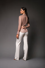 Full-length rear studio perspective of a model showcasing the shimmering, sheer rose gold variation of the Anita silk lurex shirt styled with tailored white high-waisted pants.