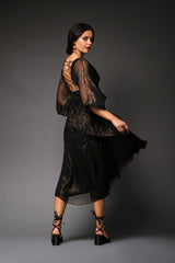 Rear studio perspective of a model turning back, highlighting the dramatic open back with intricate lace-up corset details and the flowing asymmetry of the metallic chiffon skirt.